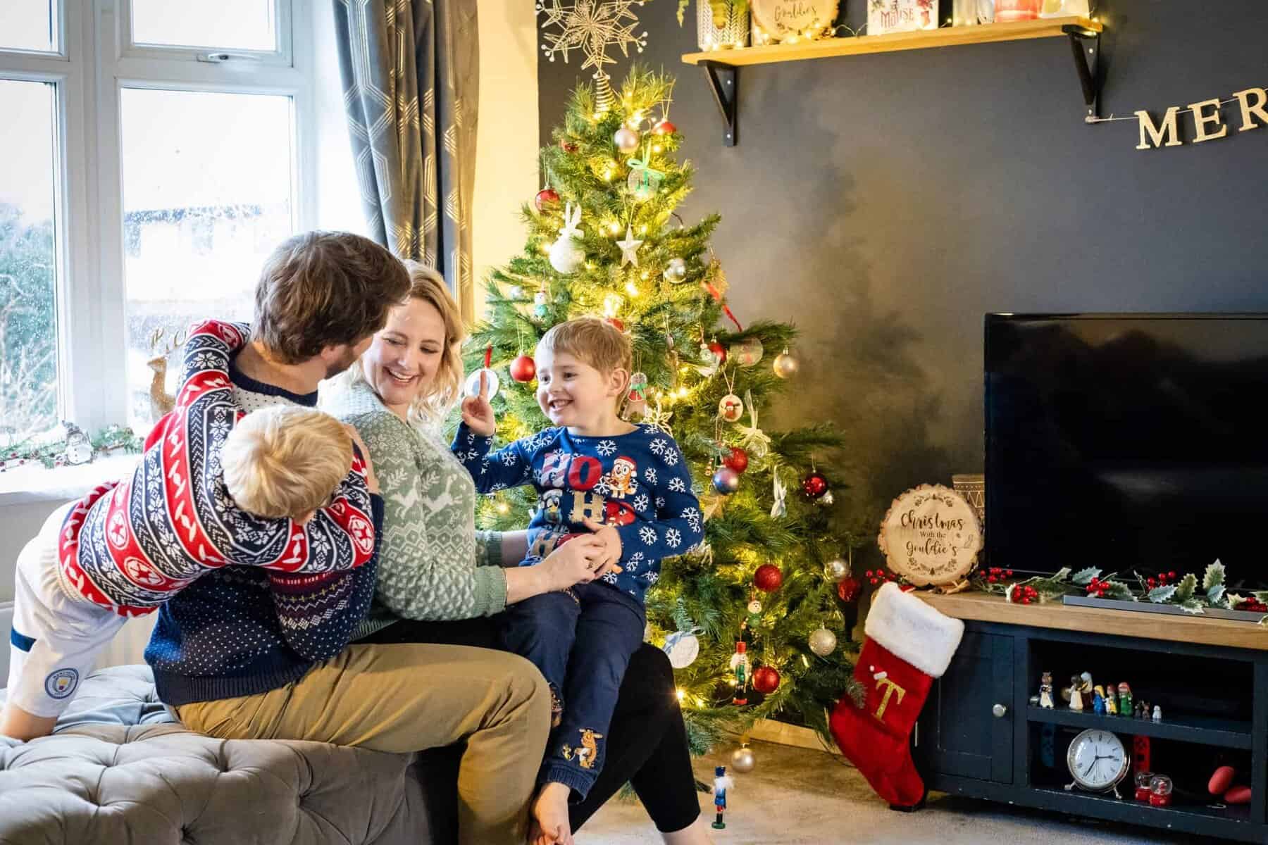 Family laughing together in front of Christmas tree. Rebecca Morgan Photography. Northants Families