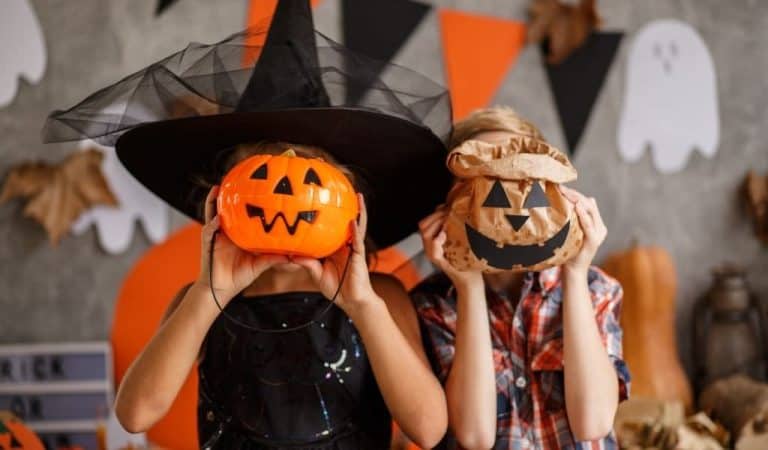 Two children holding pumpkins to their face. From Pumpkin picking to spooky train rides, there is loads of Halloween Events in Northants this year.