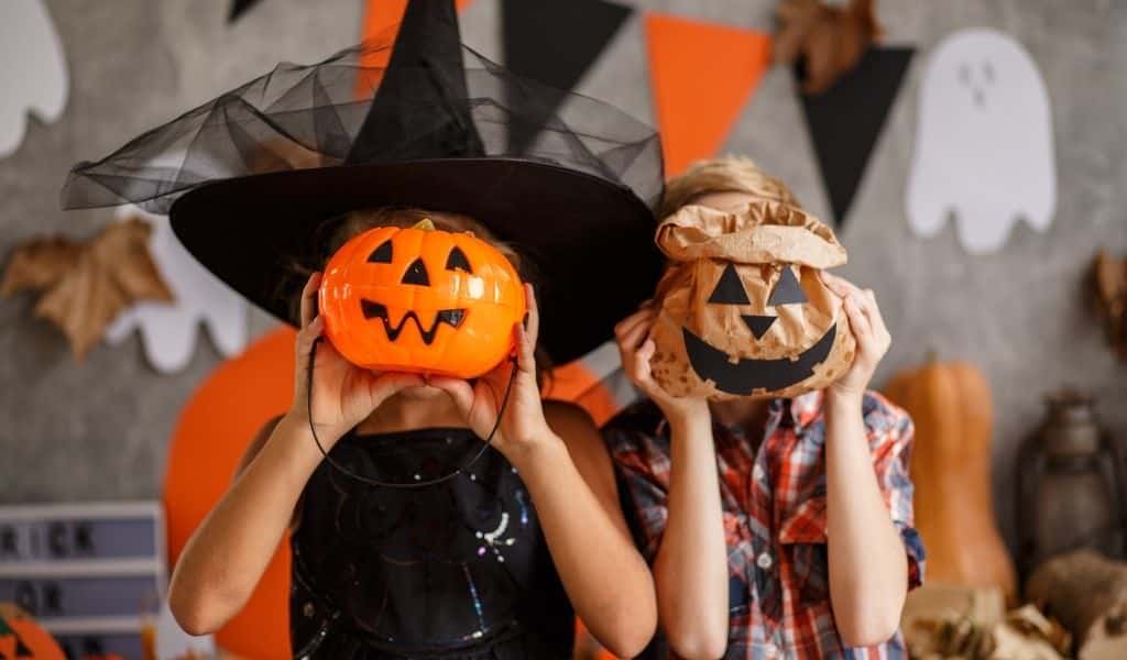 Two children holding pumpkins to their face. From Pumpkin picking to spooky train rides, there is loads of Halloween Events in Northants this year.