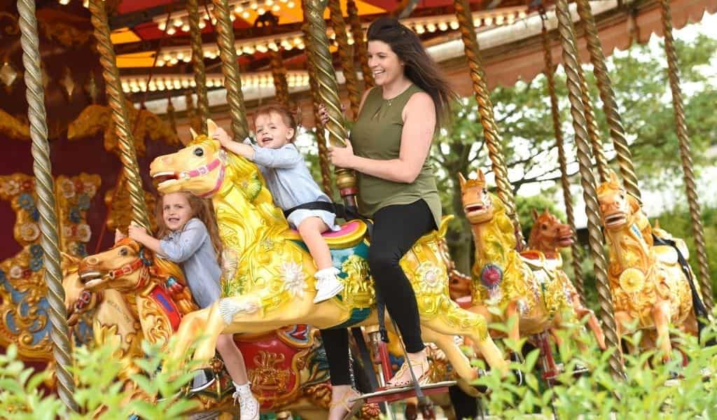 Mum and daughters riding carousel at Wicksteed Park