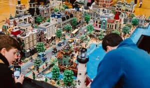 A boy and man building a large lego model of a city
