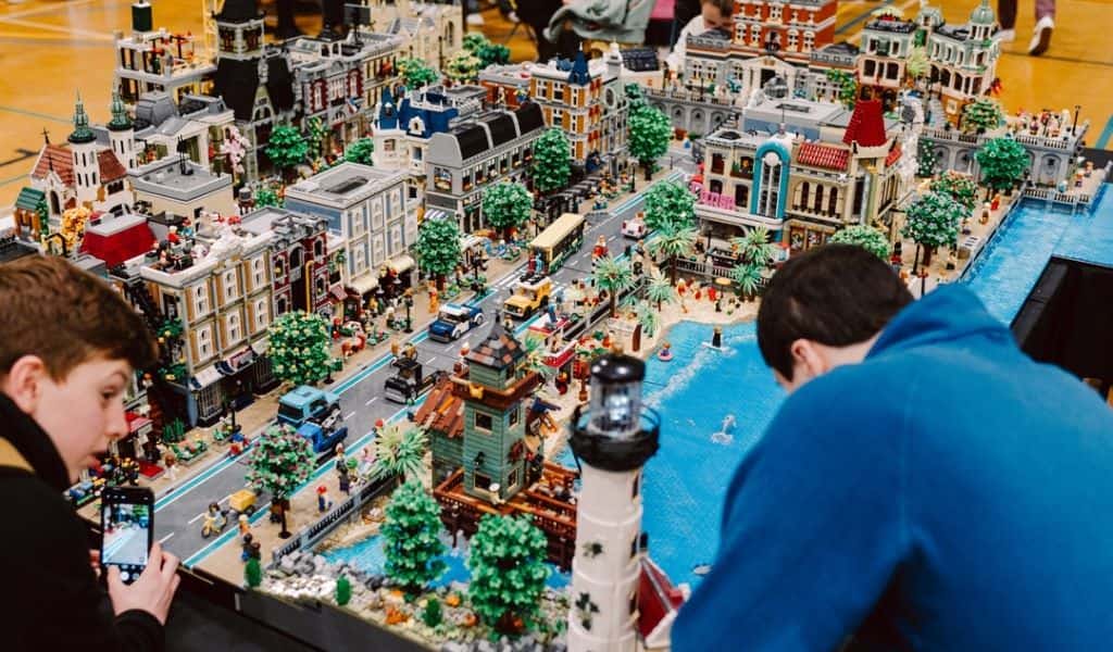 A boy and man building a large lego model of a city
