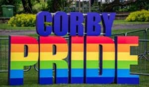 Corby Pride lettering in rainbow colours in a park