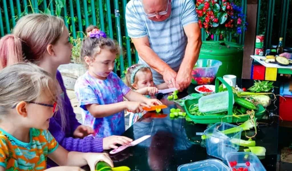 Man and children cutting vegetables outside