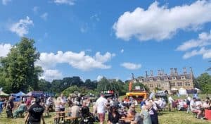 A crowd of people sitting on lawn outside Holdenby house