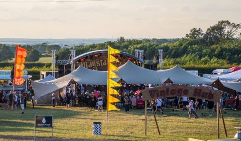 Aerial view of festival full of people with a large tent and a stage in the background