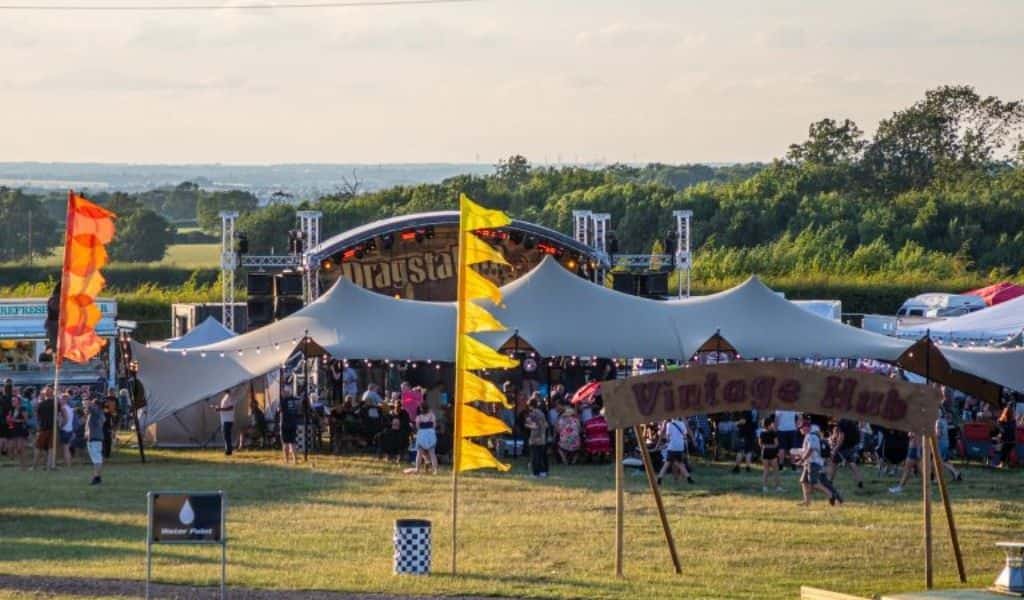 Aerial view of festival full of people with a large tent and a stage in the background