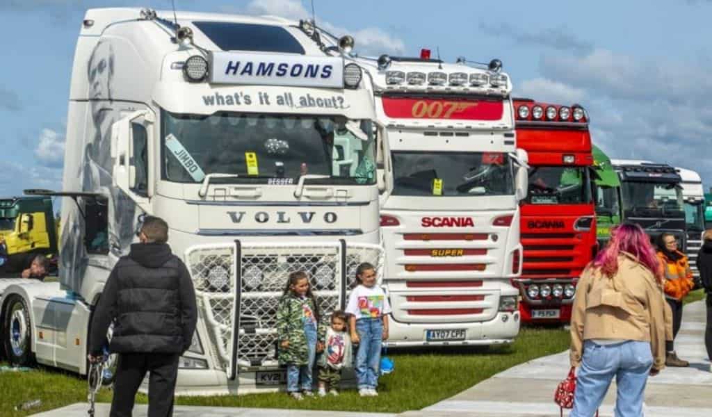 Two children standing in front of row of large trucks