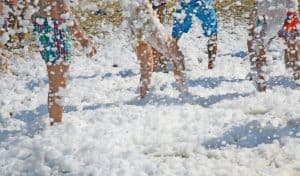 Children's legs covered in bubbly white foam during an outdoor foam party