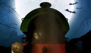 The front of a green and red train set against a spooky dark night sky with branches and bats to the sides